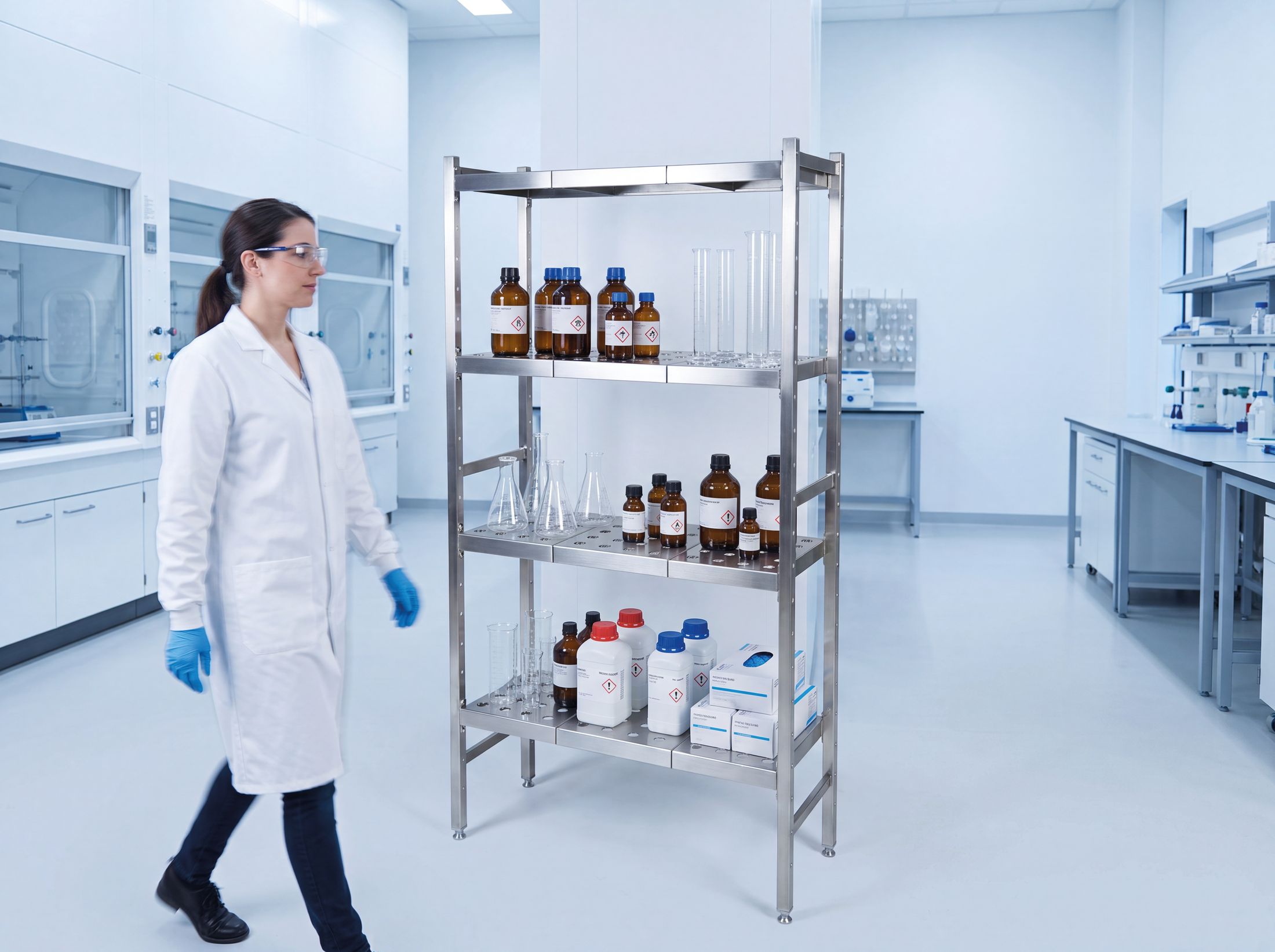 Researcher walking past a stainless steel shelving unit in a laboratory
